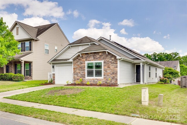 craftsman-style house with stone siding, an attached garage, driveway, and a front yard
