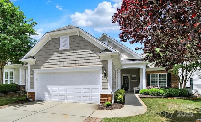 view of front of house with driveway, a front yard, an attached garage, and stone siding