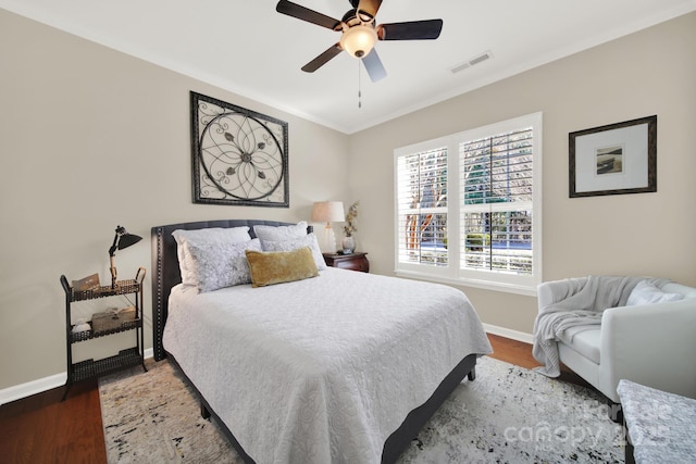 bedroom with crown molding, a ceiling fan, visible vents, baseboards, and wood finished floors