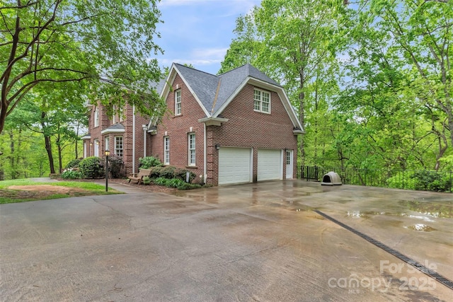 view of front of house featuring fence, an attached garage, driveway, and brick siding