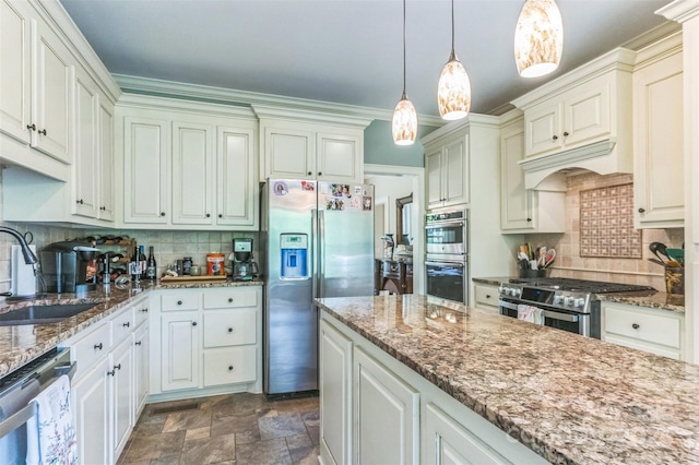 kitchen featuring tasteful backsplash, a sink, stone finish flooring, appliances with stainless steel finishes, and decorative light fixtures