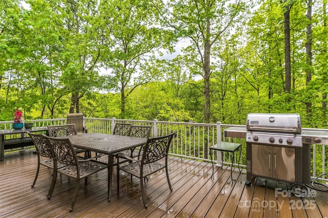 wooden terrace featuring a grill and outdoor dining space