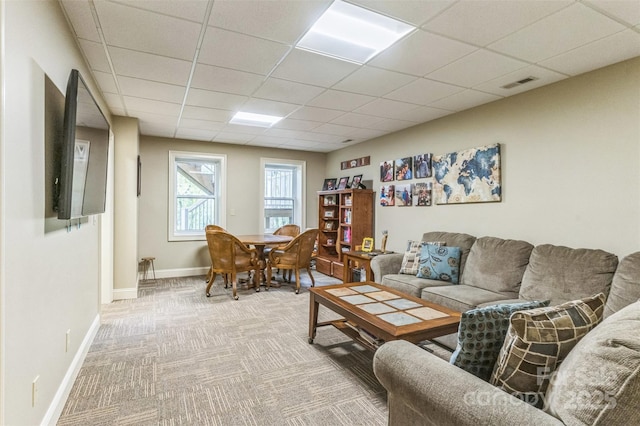 carpeted living area with baseboards, visible vents, and a drop ceiling