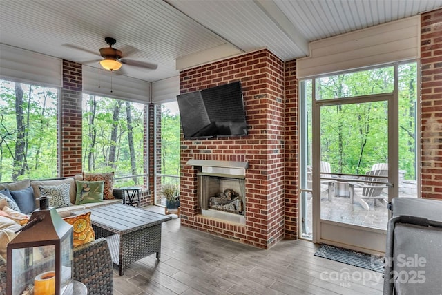 sunroom / solarium featuring a ceiling fan and an outdoor living space with a fireplace