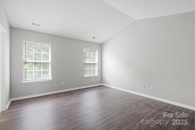 spare room featuring lofted ceiling, a textured ceiling, dark wood-style floors, and baseboards