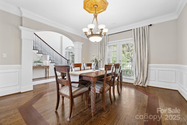 18730 Floyd Ct, Davidson, NC 28036 - dining area featuring arched walkways, ornate columns, ornamental molding, a wainscoted wall, and stairs