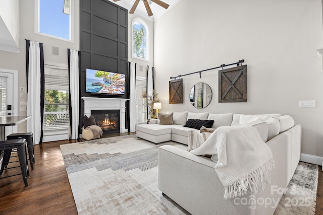 18730 Floyd Ct, Davidson, NC 28036 - living area with a high ceiling, ceiling fan, dark wood-style floors, a large fireplace, and baseboards