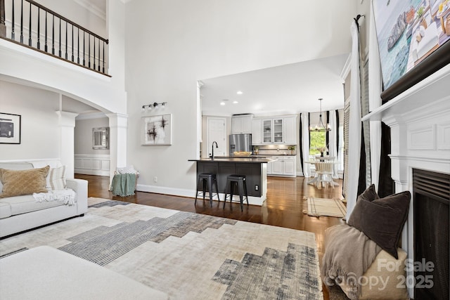 18730 Floyd Ct, Davidson, NC 28036 - living room featuring decorative columns, a towering ceiling, arched walkways, dark wood-style floors, and ornamental molding