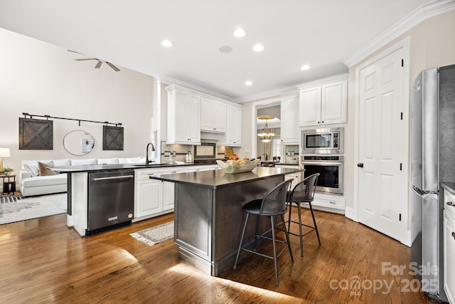 18730 Floyd Ct, Davidson, NC 28036 - kitchen featuring appliances with stainless steel finishes, dark countertops, a breakfast bar, a sink, and white cabinets