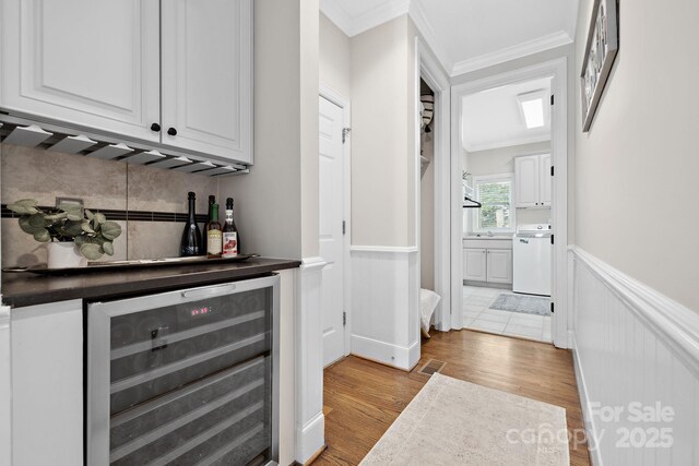 18730 Floyd Ct, Davidson, NC 28036 - indoor dry bar featuring beverage cooler, a wainscoted wall, dishwashing machine, light wood-style flooring, and ornamental molding