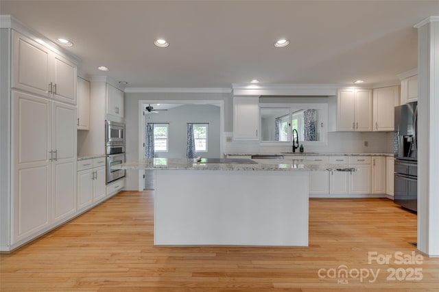 kitchen featuring crown molding, white cabinetry, appliances with stainless steel finishes, and a sink