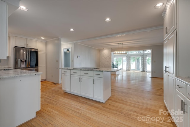 kitchen featuring stainless steel fridge, ornamental molding, light wood finished floors, and white cabinets