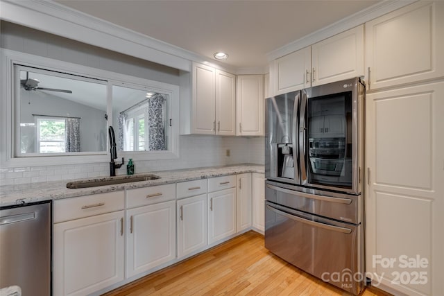 kitchen with a sink, appliances with stainless steel finishes, backsplash, and lofted ceiling