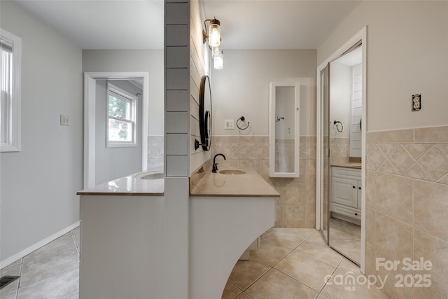 full bath featuring tile patterned flooring, wainscoting, vanity, and tile walls