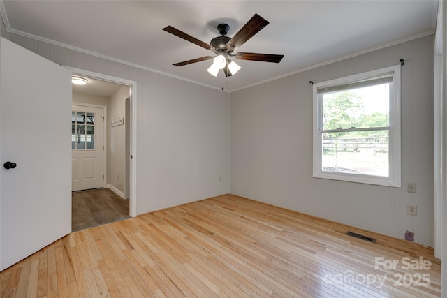empty room featuring crown molding, ceiling fan, visible vents, and hardwood / wood-style flooring