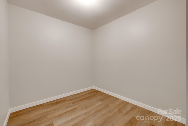 empty room featuring baseboards and light wood finished floors