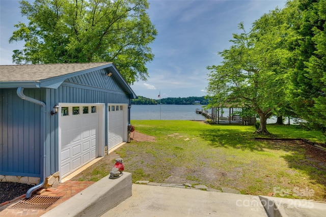 view of yard with a water view, an outbuilding, and a detached garage