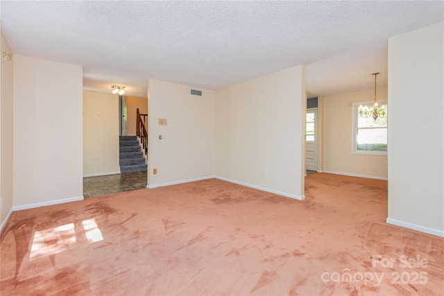 carpeted empty room featuring stairway, baseboards, an inviting chandelier, and visible vents