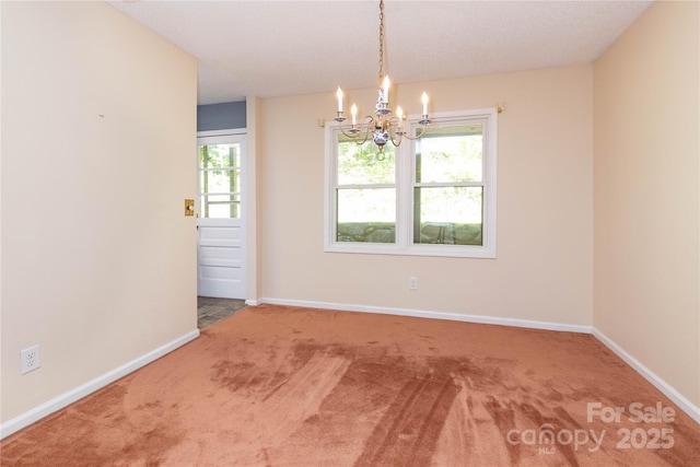 spare room with baseboards, a wealth of natural light, carpet flooring, and a notable chandelier