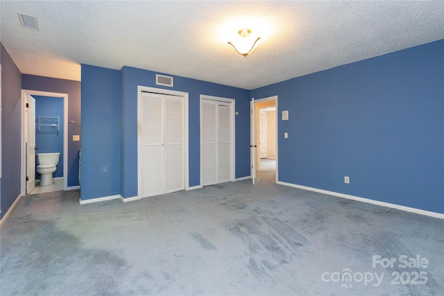 unfurnished bedroom featuring baseboards, two closets, carpet floors, and visible vents