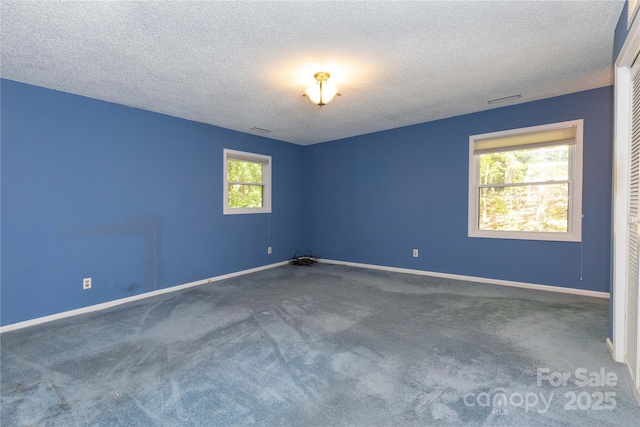 carpeted empty room featuring a textured ceiling and baseboards