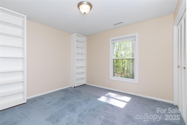 unfurnished bedroom with baseboards, carpet flooring, a textured ceiling, and visible vents