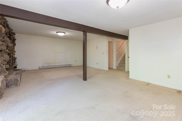 finished below grade area featuring light colored carpet, a textured ceiling, stairs, and baseboard heating