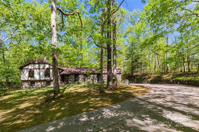view of front of property featuring stone siding, a front yard, and concrete driveway