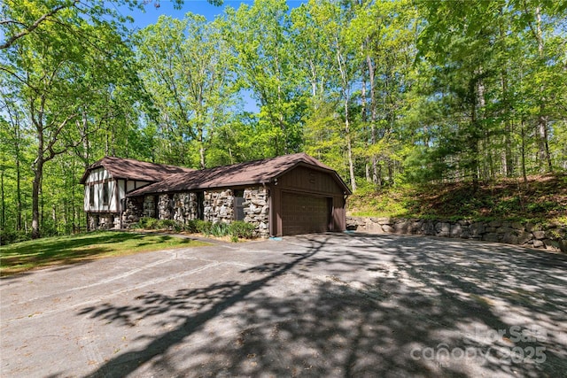 view of side of home with aphalt driveway and stone siding