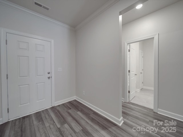 entryway with crown molding, baseboards, wood finished floors, and visible vents
