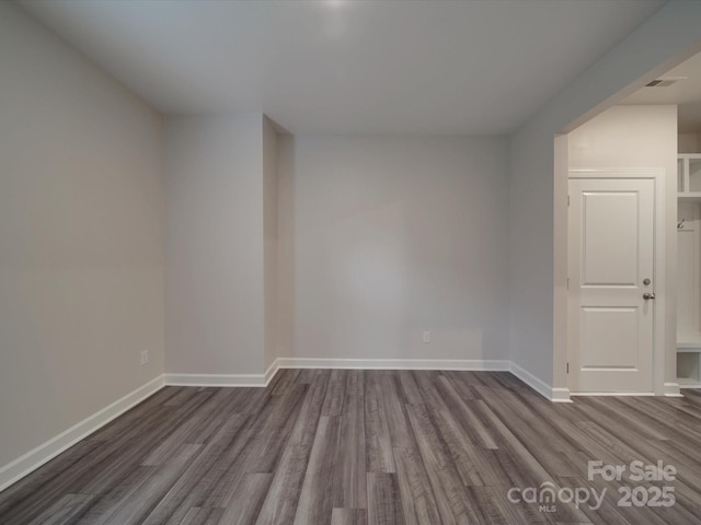 unfurnished room with baseboards and dark wood-style flooring