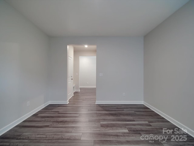 empty room featuring baseboards and dark wood-type flooring