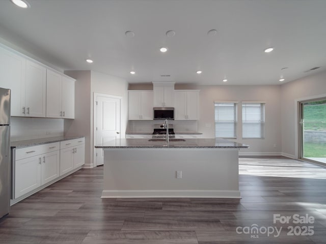 kitchen with a sink, dark stone countertops, appliances with stainless steel finishes, and white cabinets