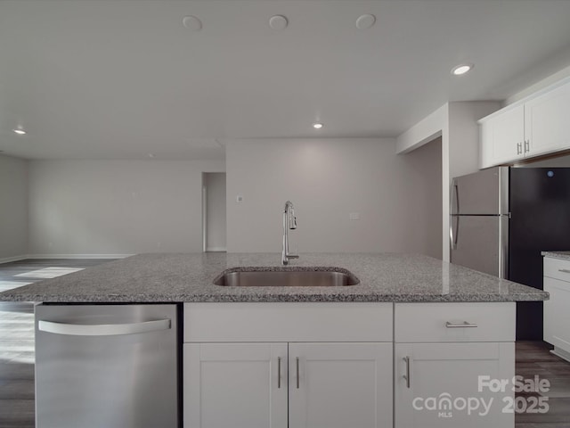 kitchen with white cabinets, light stone countertops, a sink, dishwasher, and dark wood-type flooring