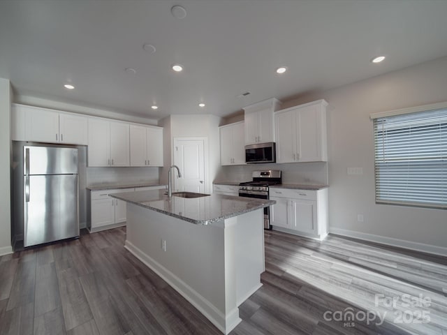 kitchen with appliances with stainless steel finishes, a sink, dark wood-type flooring, recessed lighting, and an island with sink