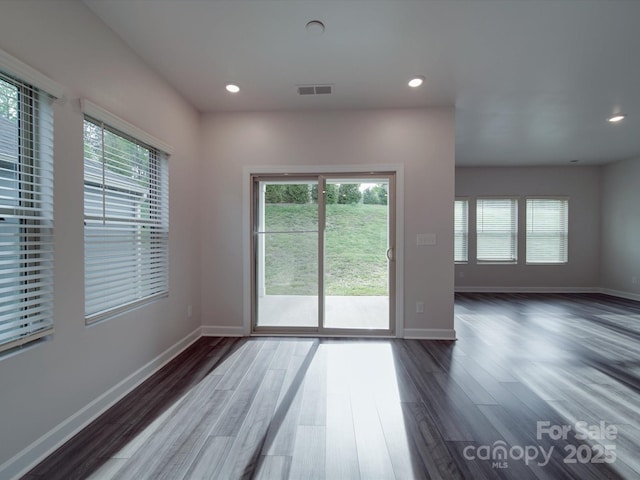 unfurnished room with a healthy amount of sunlight, wood finished floors, and visible vents
