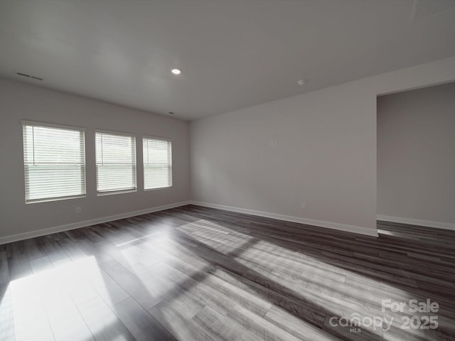 spare room featuring visible vents, recessed lighting, baseboards, and dark wood-type flooring