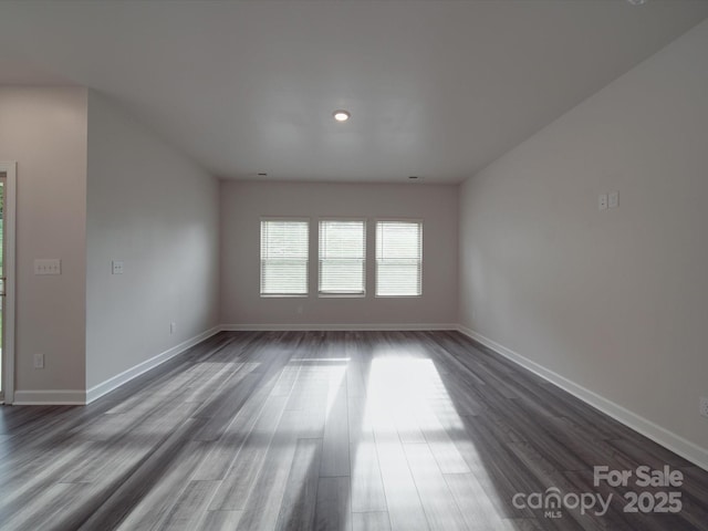 unfurnished living room featuring baseboards and dark wood-style flooring