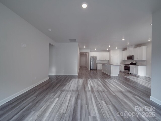unfurnished living room with visible vents, baseboards, light wood-style floors, recessed lighting, and a sink