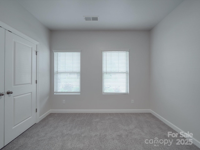 carpeted empty room featuring baseboards and visible vents