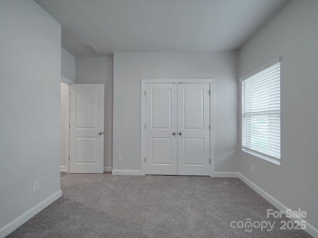unfurnished bedroom featuring baseboards, visible vents, carpet, and a closet