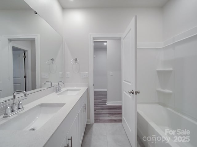 full bath with double vanity, baseboards, a sink, and tile patterned flooring