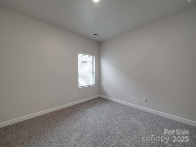 carpeted spare room featuring baseboards