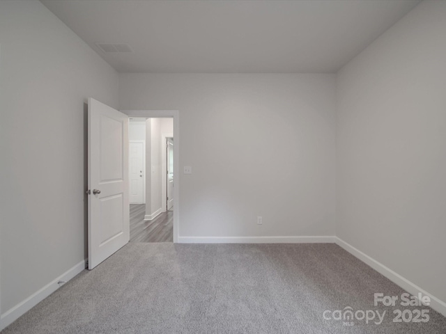 carpeted empty room featuring baseboards and visible vents