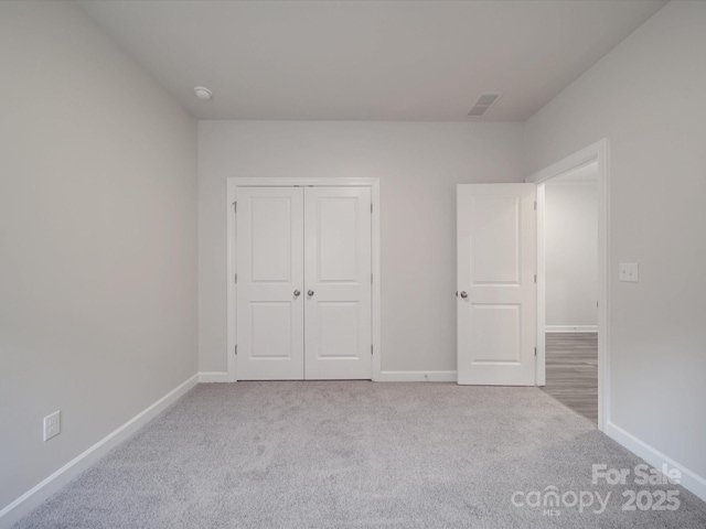 unfurnished bedroom featuring carpet floors, baseboards, visible vents, and a closet
