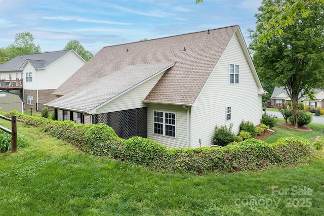 back of property featuring a yard and roof with shingles