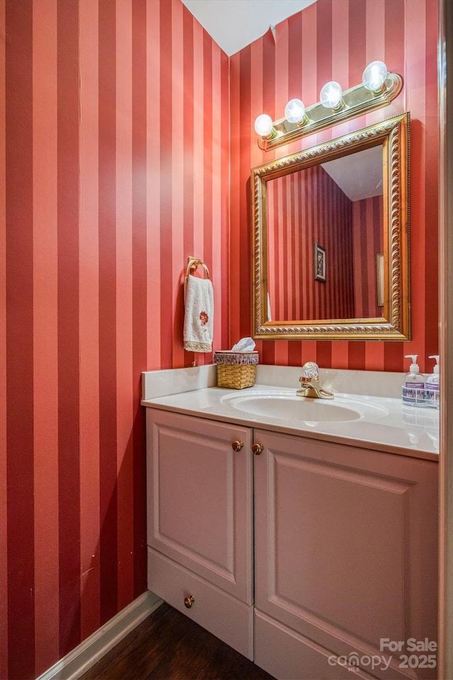 bathroom featuring wallpapered walls, wood finished floors, and vanity