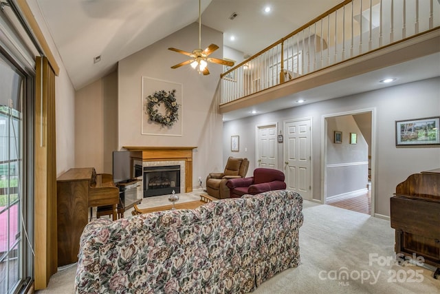 living room with carpet floors, ceiling fan, a glass covered fireplace, baseboards, and high vaulted ceiling