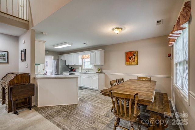 kitchen featuring a sink, visible vents, light countertops, white cabinets, and freestanding refrigerator