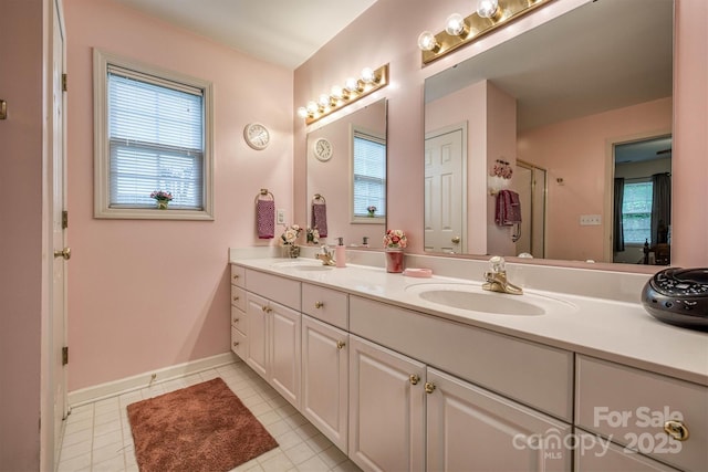 bathroom with double vanity, an enclosed shower, tile patterned flooring, and a sink